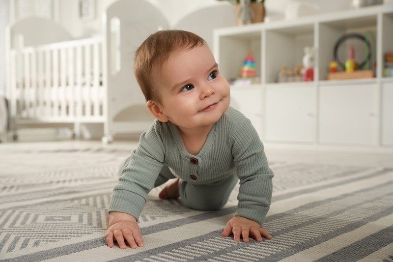 Cute baby crawling on floor at home